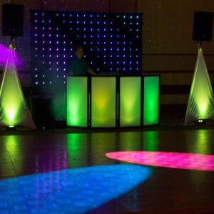 A wedding DJ set up with colorful lights and speakers.