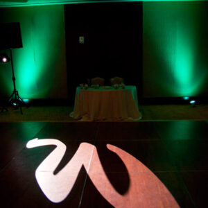 A green lit dance floor with a letter w on it.