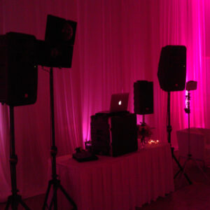 Dj equipment on a table in front of a pink curtain.