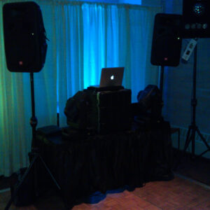 A dj set up in a room with a laptop and speakers.