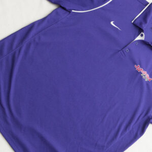 An apparel is a purple Nike polo shirt on a bed.