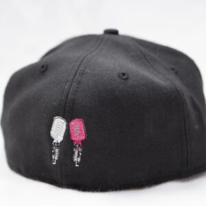 Apparel: A black hat with two pink ice cream sticks on it.