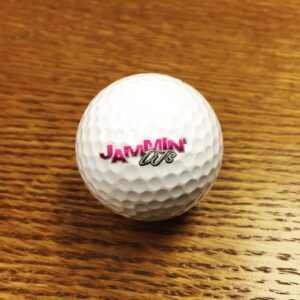 A white golf ball with a pink logo on it, ideal for golf apparel enthusiasts.