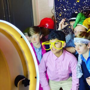 A group of boys are posing for pictures in front of a mirror at a bar mitzvah.