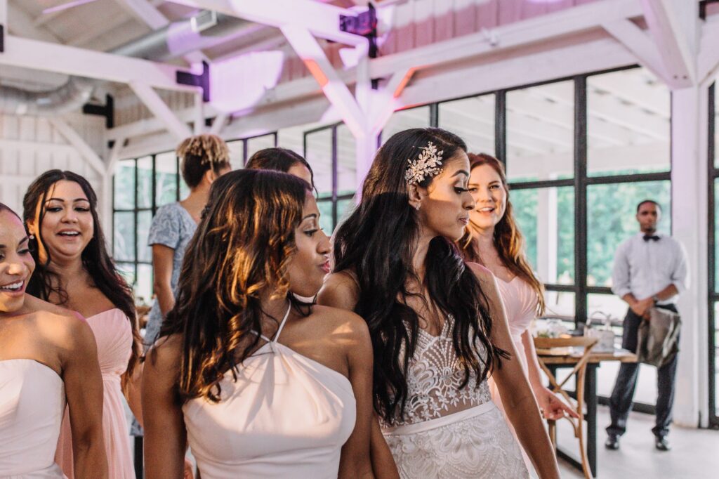 A bride and her bridesmaids are dancing in a barn.