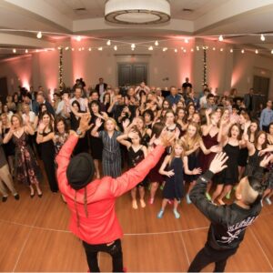 A group of people dancing at a BAR Mitzvah on a dance floor.