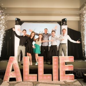 A group of people posing in front of a sign that says allie at a BAR Mitzvah.