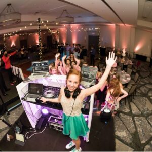 A young girl with a DJ set up at a BAR Mitzvah party.