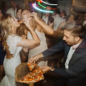 A bride and groom sharing a slice of pizza at a wedding reception.