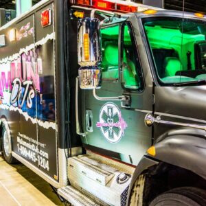 A black ambulance truck is on display at a convention. The exhibit provides an overview of the vehicle, showcasing its advanced medical equipment and specialized features.