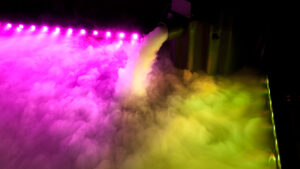 A mesmerizing rainbow colored smoke is billowing out of a futuristic DJ equipment.