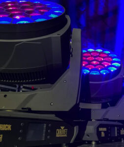 A group of DJ equipment with moving lights on a stage.