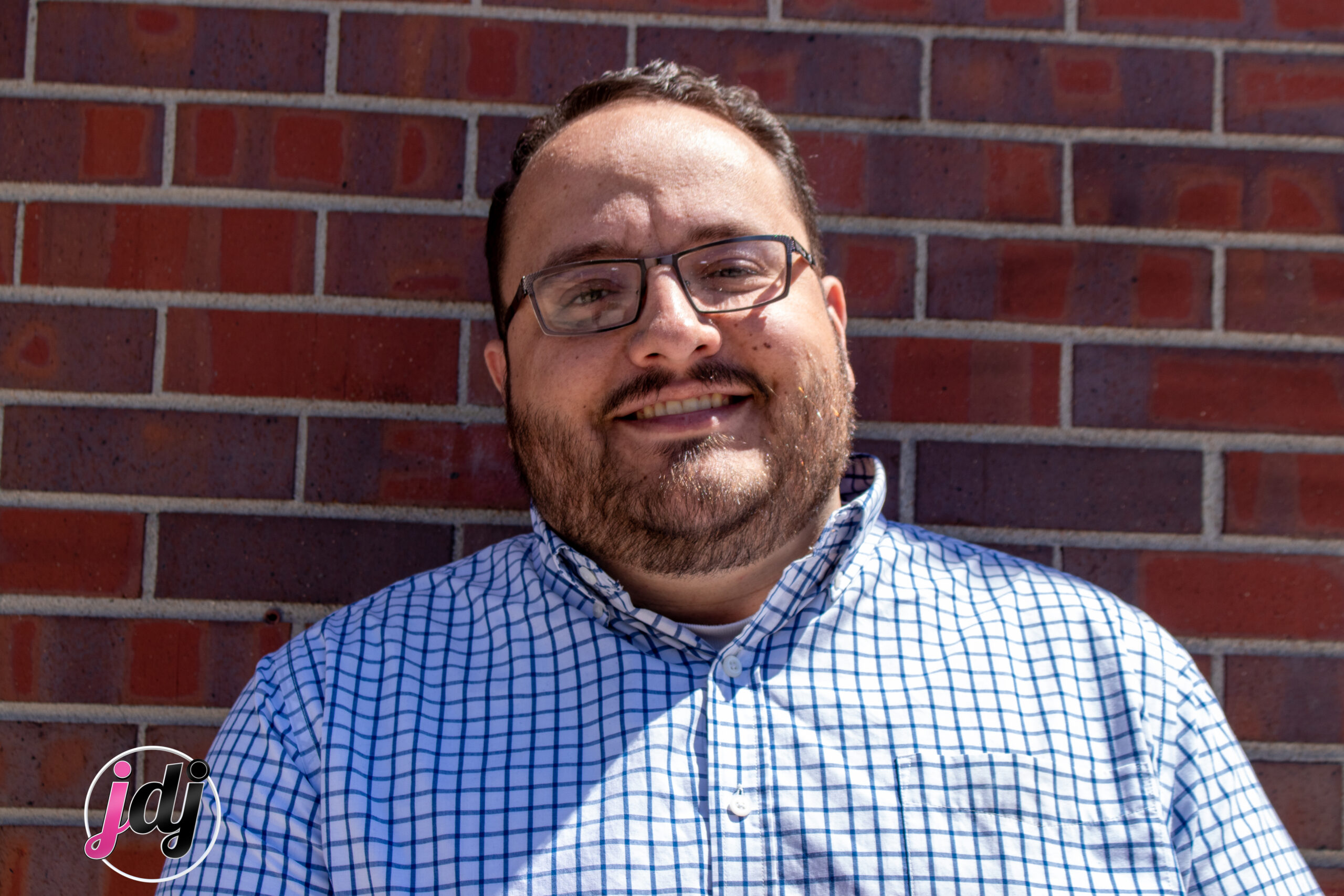 A man smiling in front of a brick wall at a bar mitzvah.