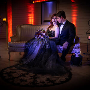 A bride and groom sitting on a couch in a dark room after their bat mitzvah celebration.