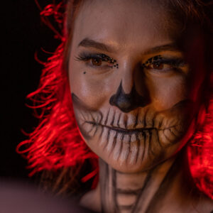 A woman with skeleton makeup and red hair poses in a photo booth rental.