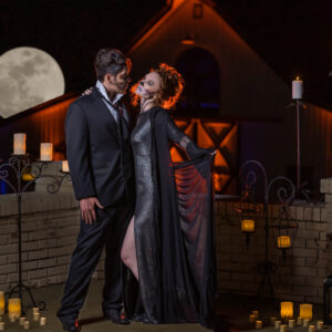 A couple in a Halloween costume standing in front of a brick wall with candles at a Denver DJ's photo booth rental.
