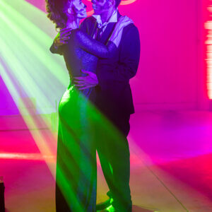 A man and woman dancing in a room with bright lights during a wedding DJ set.
