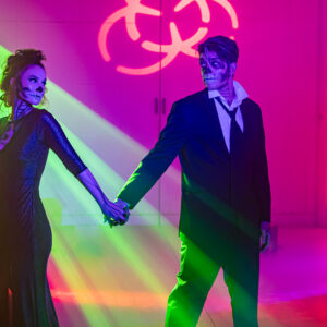 A man and woman holding hands in a dark room with a Denver DJ playing in the background.