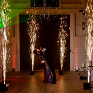 A man and woman kissing in front of fireworks at a bar mitzvah.