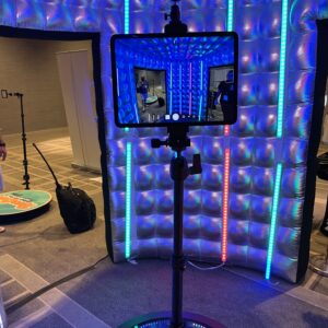 A person is using a tablet in a room with lights to search for a Denver DJ and photo booth rental for their wedding.