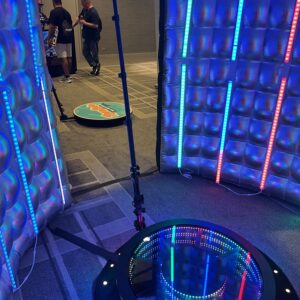 A group of people are standing in a room with lights at a bar mitzvah where the wedding DJ provides the music.