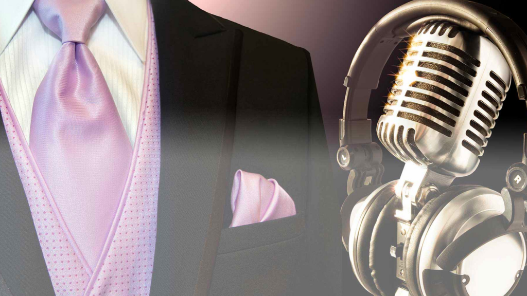 A Denver DJ in a suit with a microphone and a pink tie.