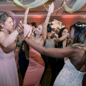 A group of bridesmaids dancing at a wedding reception, energized by the DJ service.