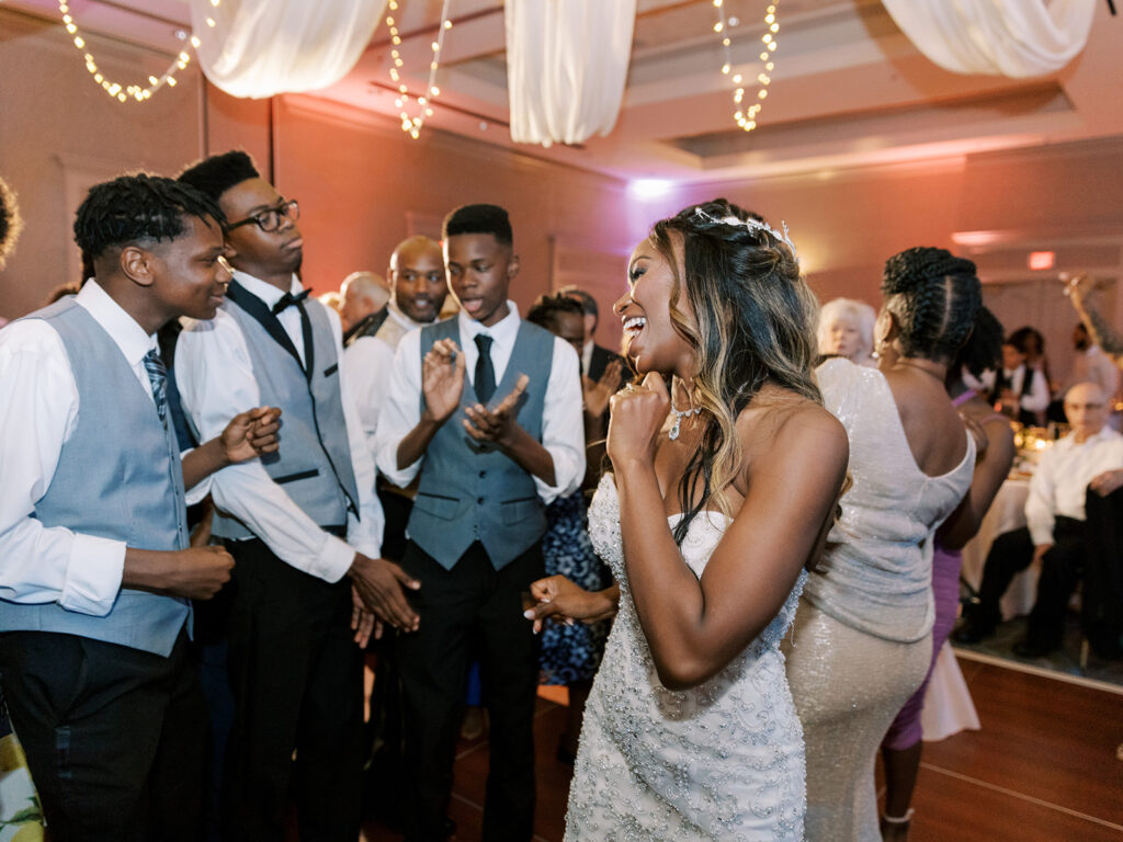A bride and groom dancing on the dance floor at a wedding reception with a photo booth rental nearby.
