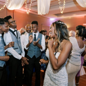 A bride and groom dancing on the dance floor at a wedding reception with a photo booth rental nearby.