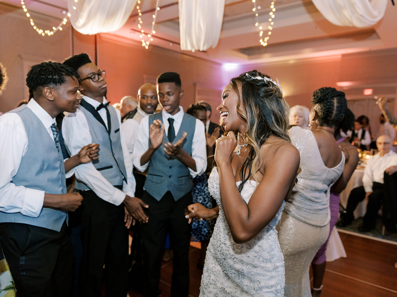 A bride and groom dancing on the dance floor at a wedding reception with a photo booth rental nearby.