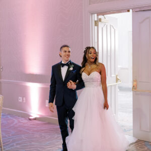 A bride and groom walking down the aisle at their wedding reception, led by vibrant tunes from a Denver DJ.