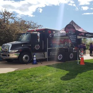 A black truck parked on a grassy area offering DJ services.