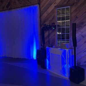 Dj set up in a barn with blue lighting, offering wedding dj service.