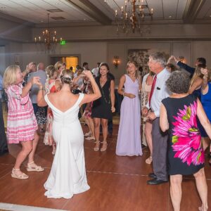 A group of people dancing at a wedding reception, entertained by a wedding DJ.