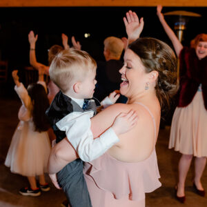 A woman is holding a little boy on the dance floor at a bat mitzvah.