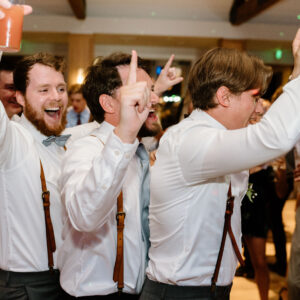 A group of groomsmen celebrating at a wedding reception with DJ service.