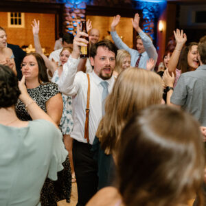 A group of people dancing at a wedding reception with a wedding DJ.