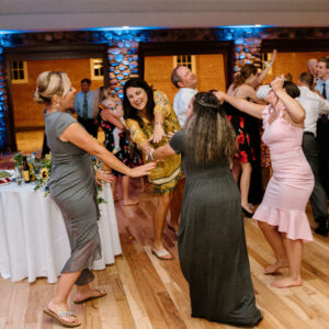 A group of people dancing at a wedding reception, entertained by a wedding DJ.