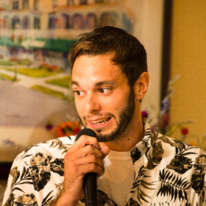 A wedding DJ in a Hawaiian shirt holding a microphone.
