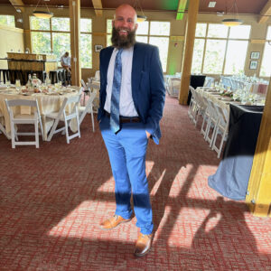 A man in a suit standing in a room during a bat mitzvah.