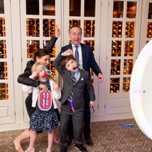 A group of people posing for a photo in front of a photo booth at a bar mitzvah.