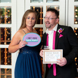 A man and woman posing for a photo in front of a mirror at a wedding DJ event.