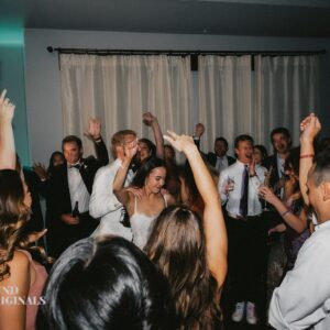 At a lively wedding reception, a couple dances surrounded by friends and family. Guests raise their hands and cheer in celebration, creating memories worthy of a gallery.