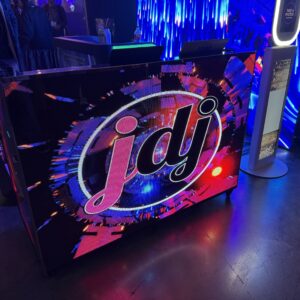 A DJ booth with colorful lights and the letters "jdj" displayed on the front.