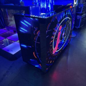 Lit DJ booth with vibrant graphics and LED lights in a dimly lit space.