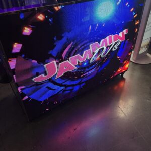 A brightly lit display screen shows the text "Jammin' DJ's" with colorful lights and abstract graphics in the background.