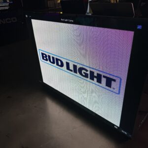 A screen displays a Bud Light logo in a dimly lit room.