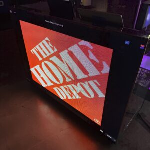 A screen displays the Home Depot logo in bold, white text on an orange background.