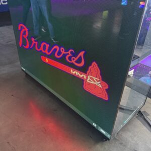 Glass display showcasing the Atlanta Braves logo with a red tomahawk against a dark background.